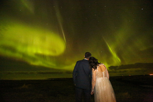 Newly wedding couple posing with aurora borealis